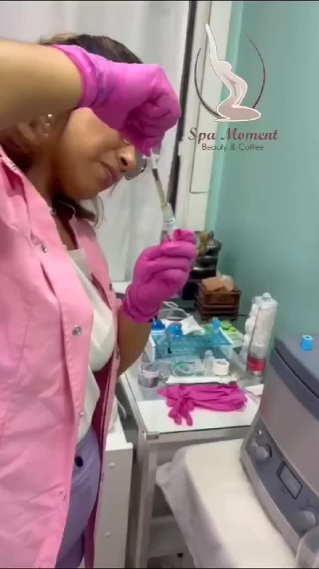 Manos con guantes rosas preparan un tubo de plasma junto al carro con la gradilla, en la cabina verde agua